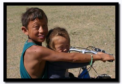 Brother and Sister Riding a Bike in the North Gobi Desert
