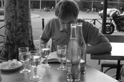 Intellectual reading a book over wine and water, Paris