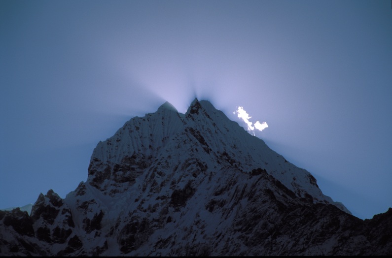Sunrise above Tramserku (crepuscular rays) seen from above Namche