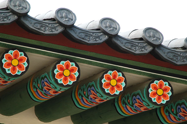 Detail of colorfully painted beams and ornate roof tiles, Gyeongbokgung