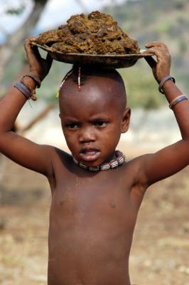 Himba child with bowl of manure