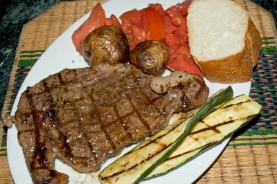 charcoal grilled ribeye steak, grilled zucchini, pan roasted potatoes, tomato salad