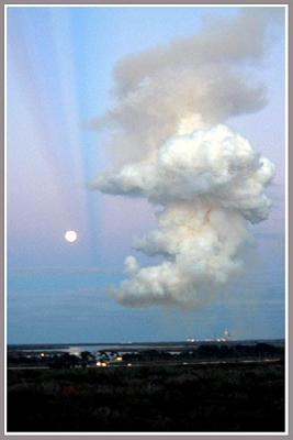 While a silent moon maintains a vigil over a man-made cloud.
