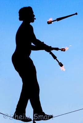 Fire juggler standing on tightrope